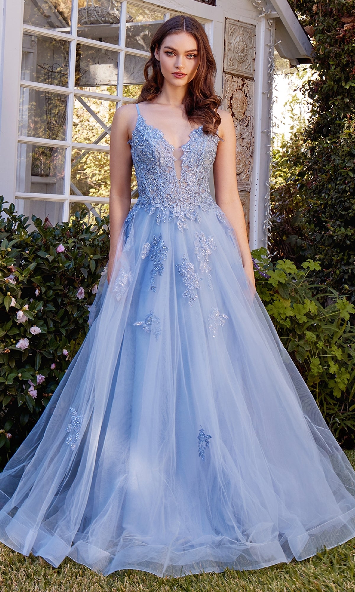 A woman stands outdoors wearing the Embroidered Long Prom Dress: Andrea & Leo A1417, a light blue, floor-length gown with an embroidered bodice and flowing tulle skirt.
